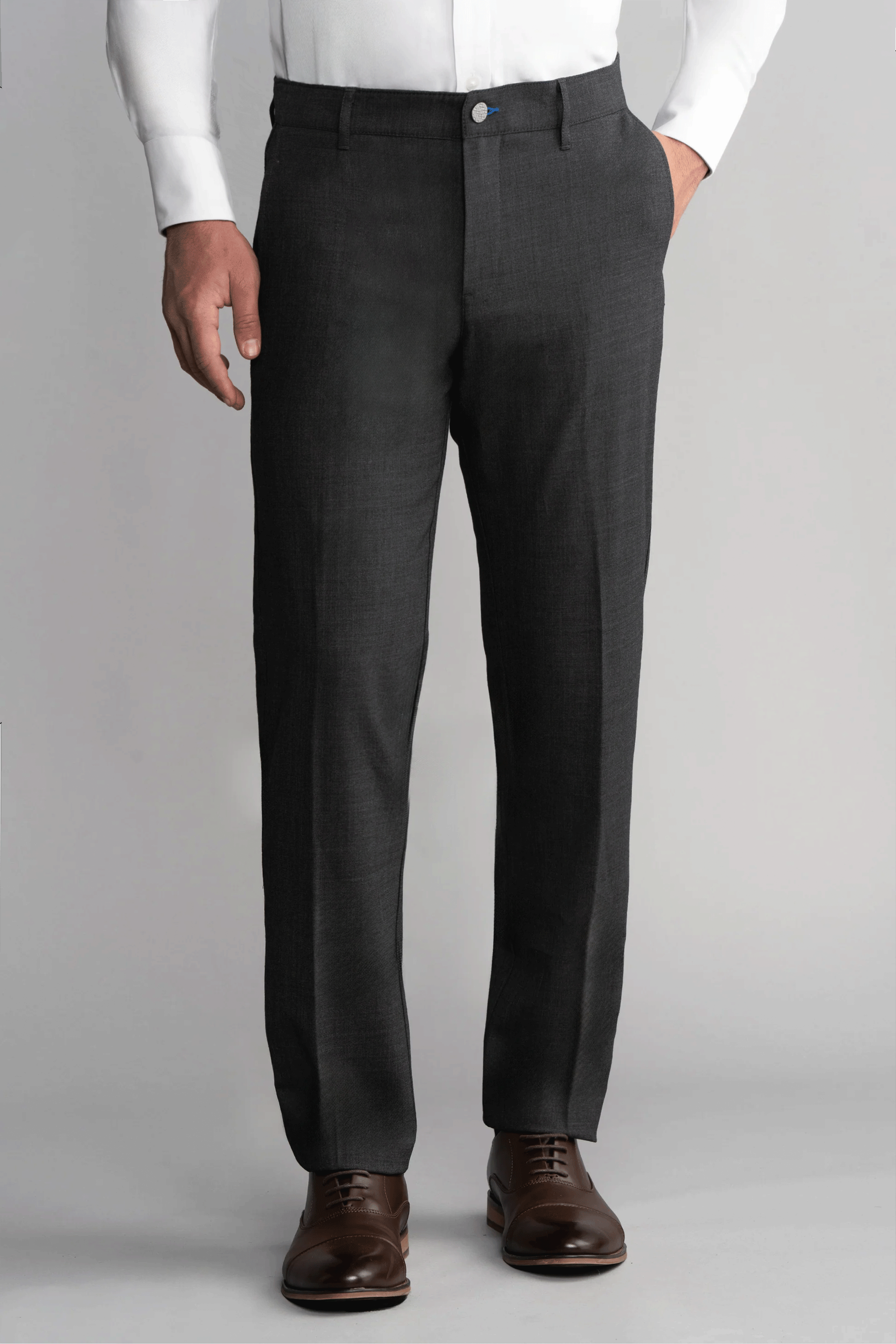 A man stands against a plain gray background wearing Twillory Hybrid Wool Pants in Grey Heather. His left hand is in his pocket, right arm by his side, and the image focuses on his lower torso and legs.