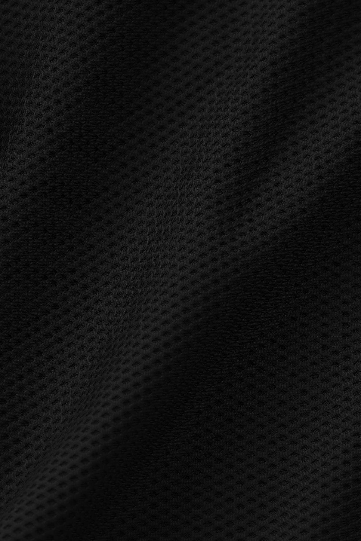 Close-up of black 360° Airflow mesh fabric by Twillory, featuring small, evenly spaced holes for breathability—perfect for the AIR Double Breasted Blazer // Black, offering softness and flexibility ideal for all-day comfort.