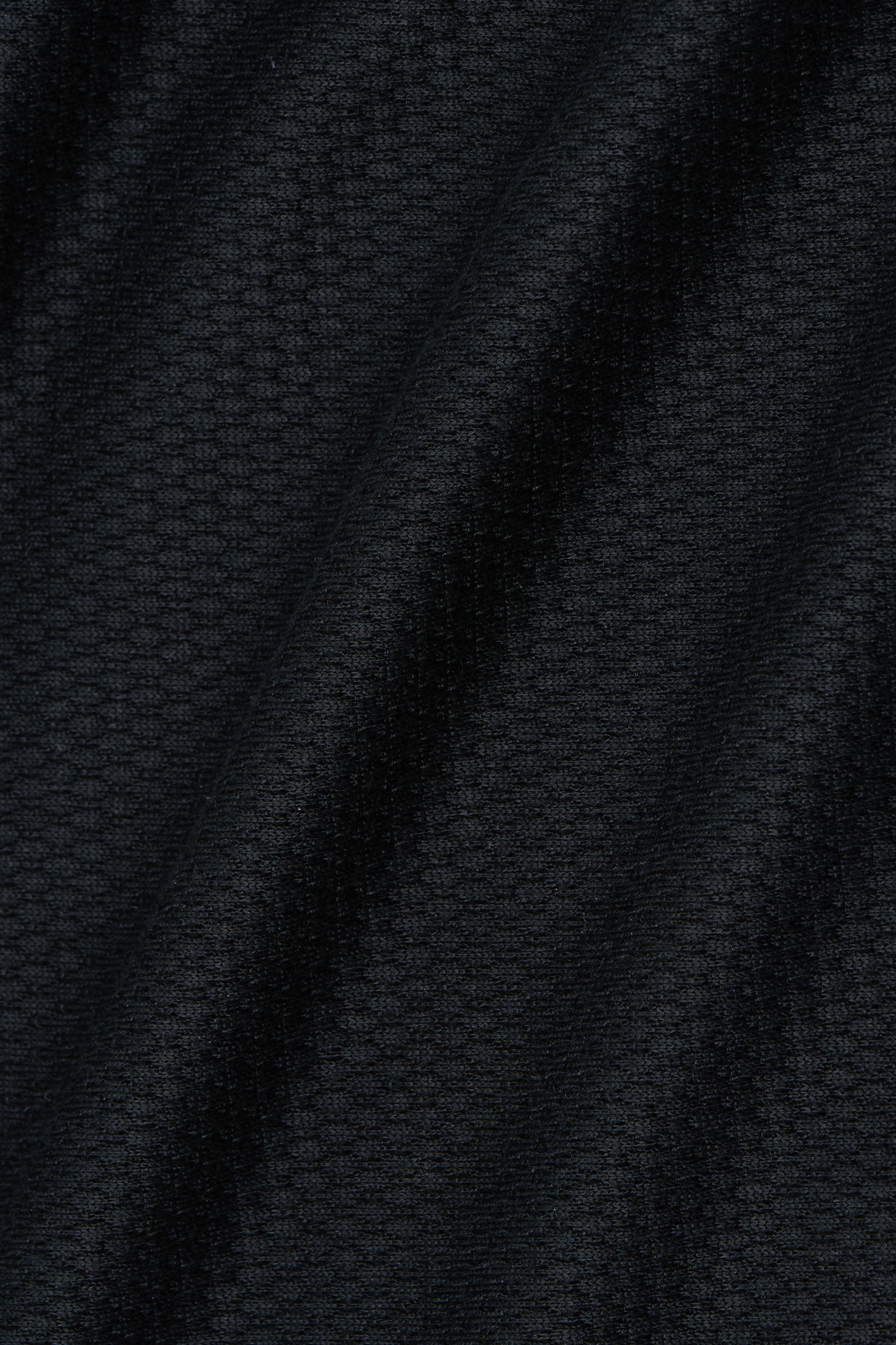 Close-up of Twillory’s Long Sleeve Sweater Polo Solid in Black shows performance knit fabric with a small waffle-like grid pattern and soft diagonal folds, highlighting its wrinkle-free, modern look and tactile surface.