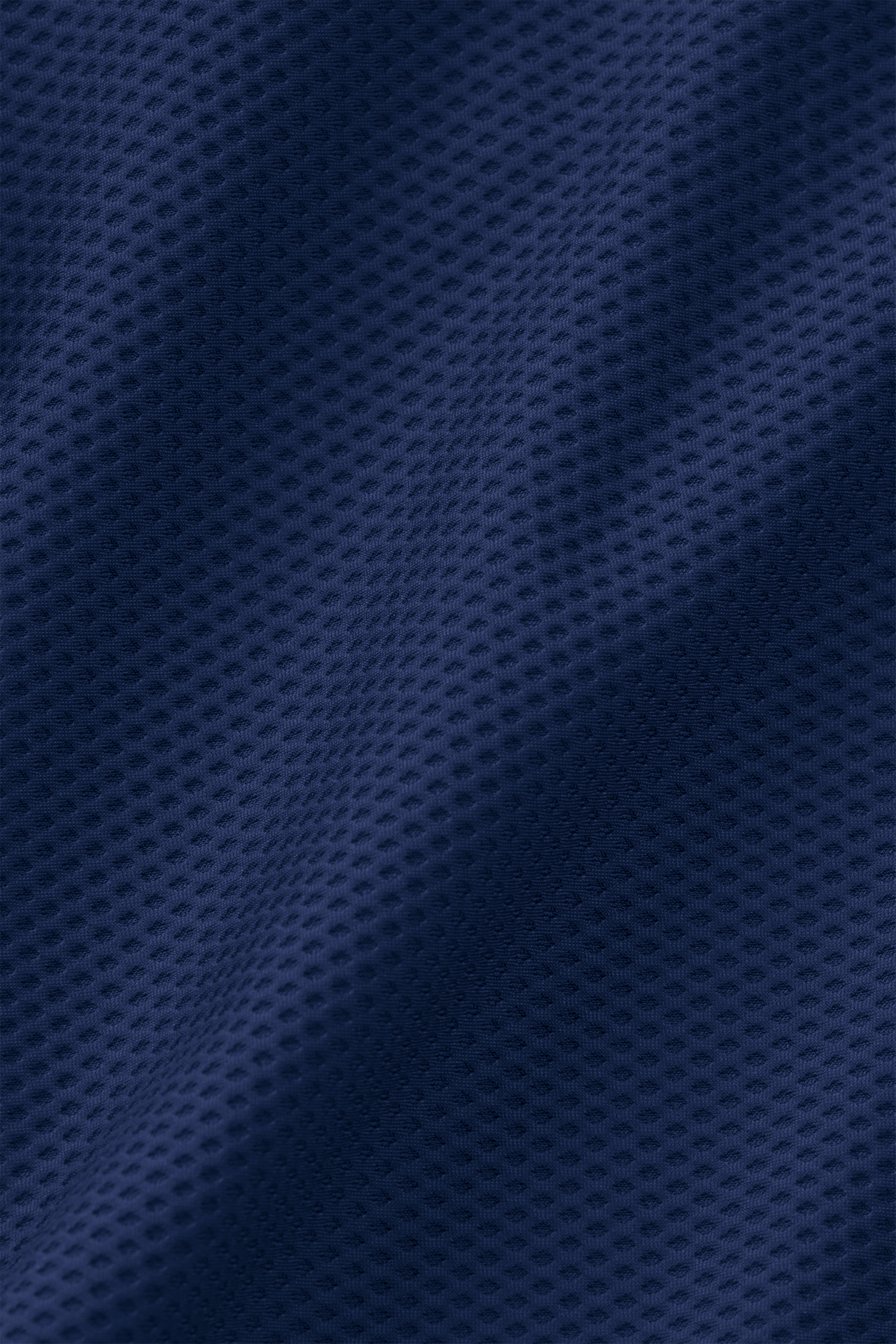 A close-up of the AIR Bomber // Blue by Twillory reveals dark blue sports mesh with wavy texture and small perforations. Its breathable, highly stretchable outer layer is perfect for athletic wear or jerseys.