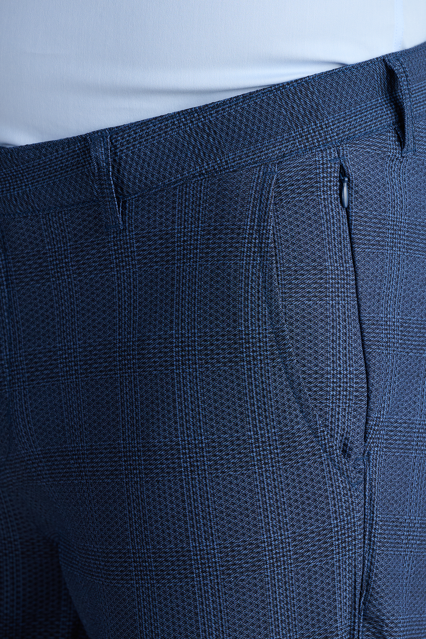 Close-up of a person wearing AIR Pants // Blue Prince of Wales, featuring a blue plaid 4-way stretch fabric and subtle checkered pattern. A light shirt is tucked in, highlighting the tailored waistband and side pocket for a comfortable fit.