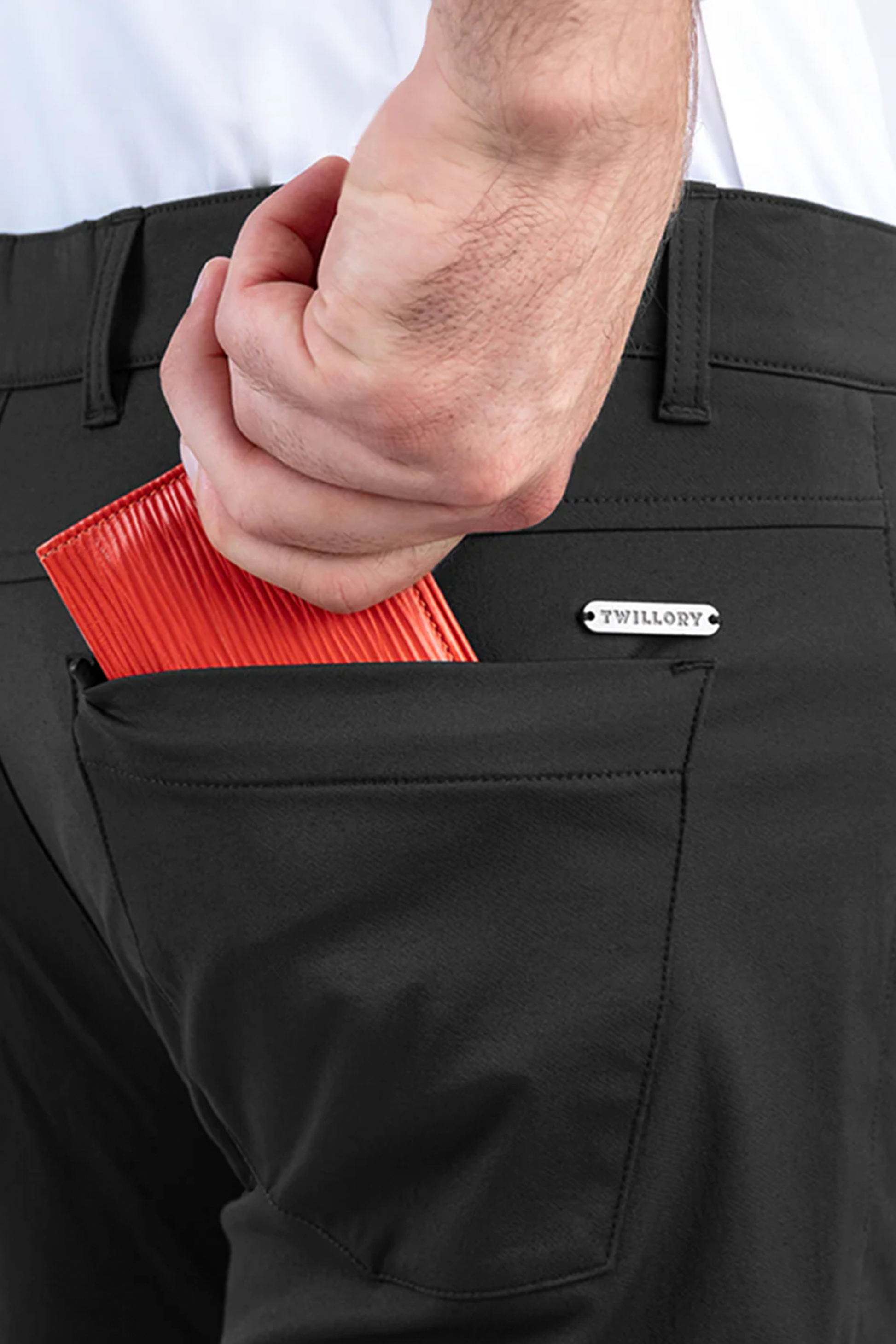 A close-up shows a hand slipping a red wallet into the back pocket of Twillory’s Performance Five Pocket // CHARCOAL pants, paired with a tucked-in white, sweat-wicking shirt for comfort and style.