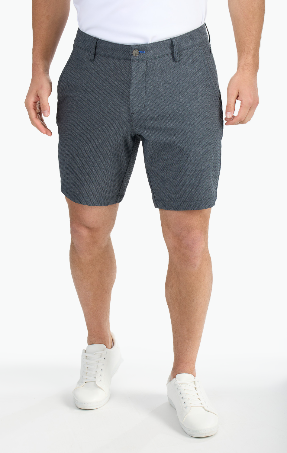 Man wearing dark gray textured shorts and white sneakers against a white background.
