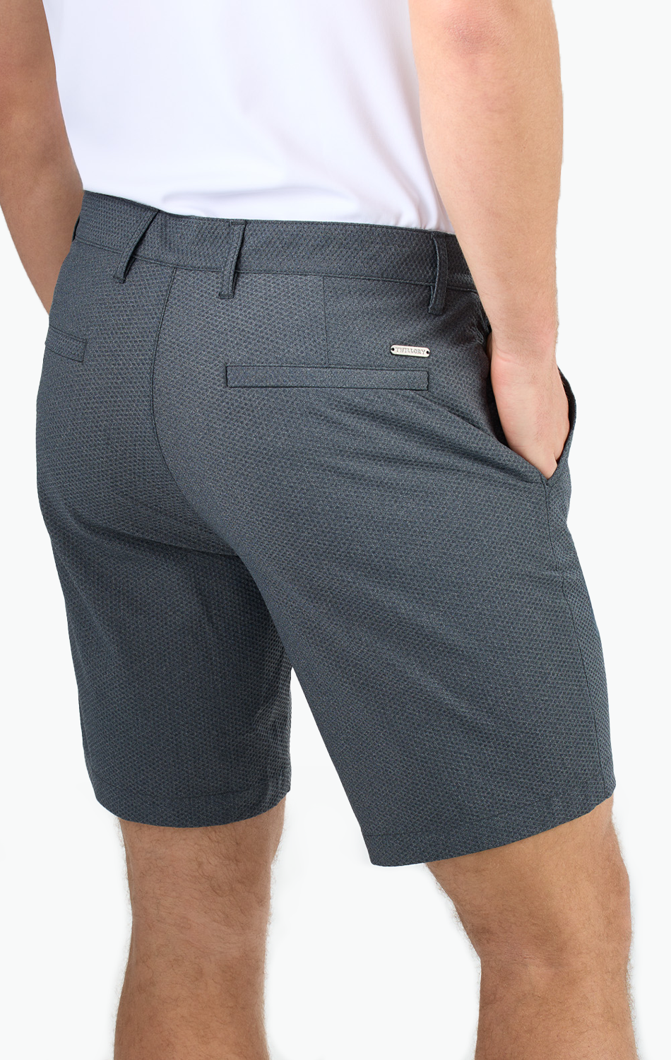Man wearing tailored gray shorts with hands in pockets, showing rear view against white background.