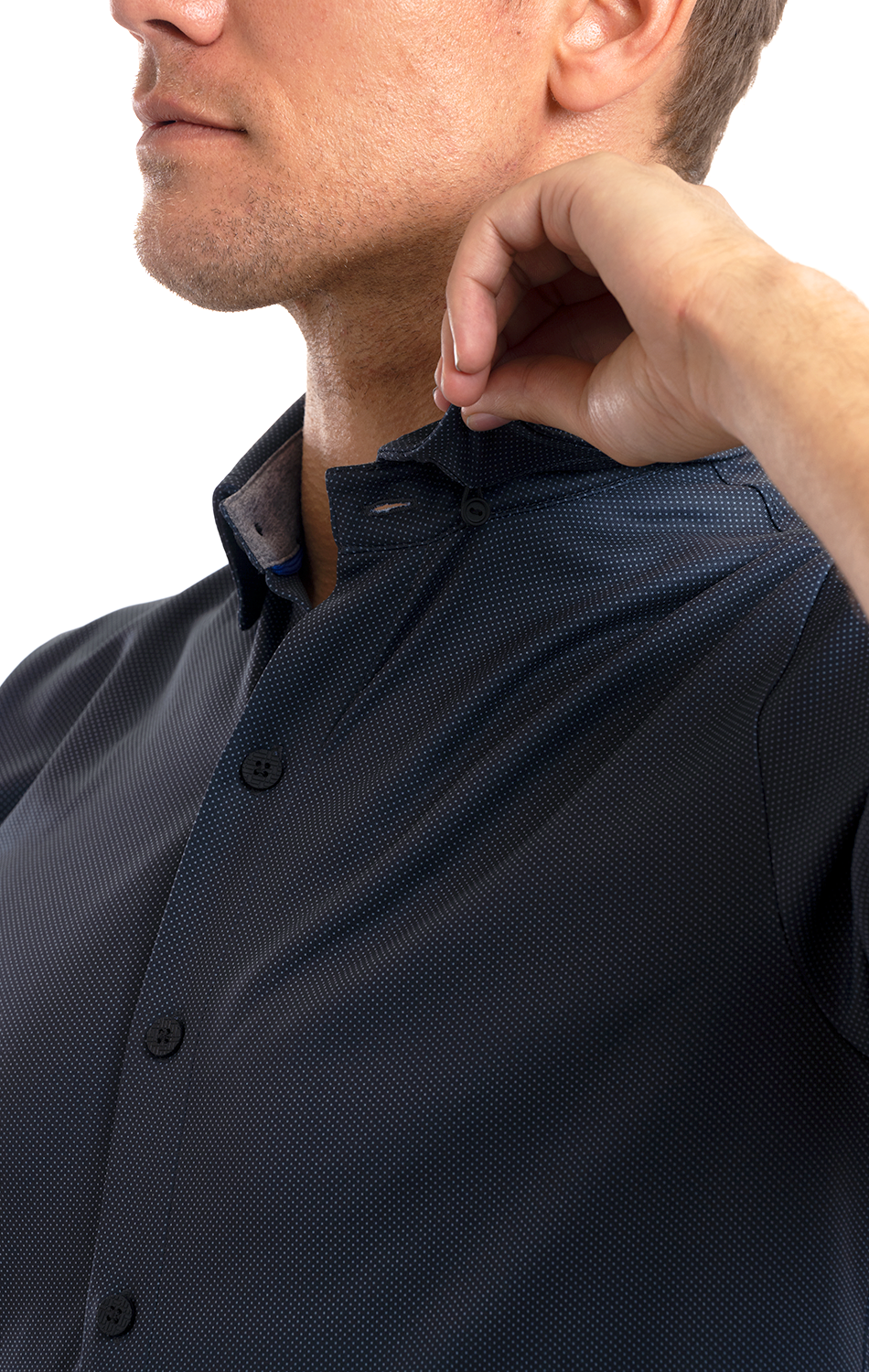 A man in a Twillory Short Sleeve Button Down Polo Dot in charcoal adjusts the collar with his right hand. The moisture-wicking, wrinkle-free shirt features a subtle dotted pattern and black buttons, standing out against a plain white background.