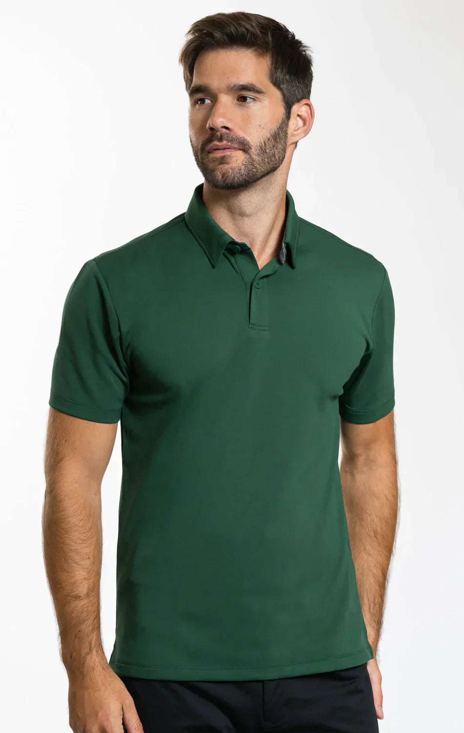A man with short brown hair and a beard wears the Twillory Short Sleeve Polo Solid in Forest, featuring moisture-wicking fabric and a collar. He stands against a plain white background, looking slightly to the side with a neutral expression.