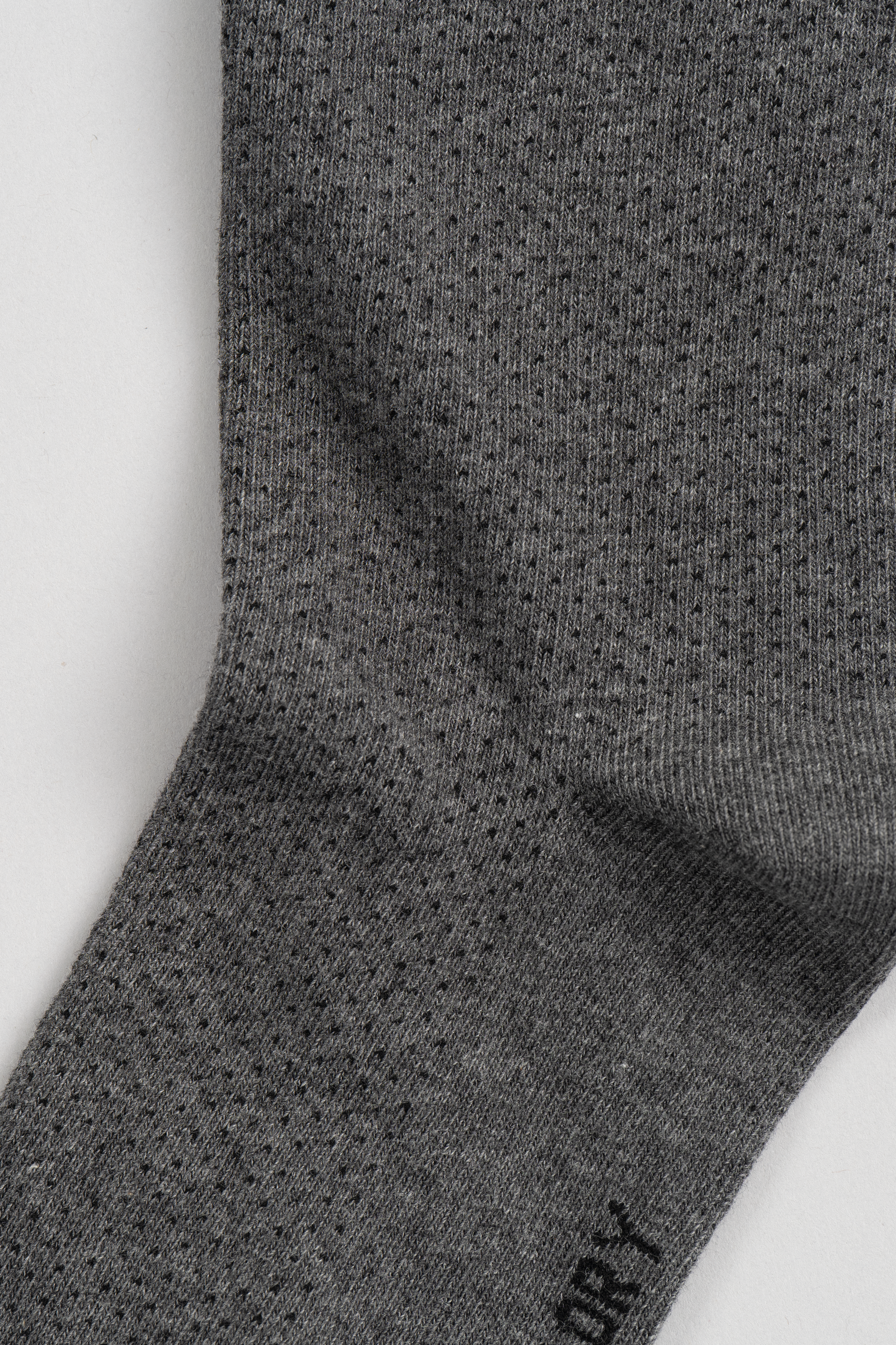 Close-up of Twillory’s Grey Pin Dot sock, featuring a subtle ribbed texture and small dotted pattern. The fine knit fabric and seamless construction make it perfect for updating your sock collection against a plain white background.