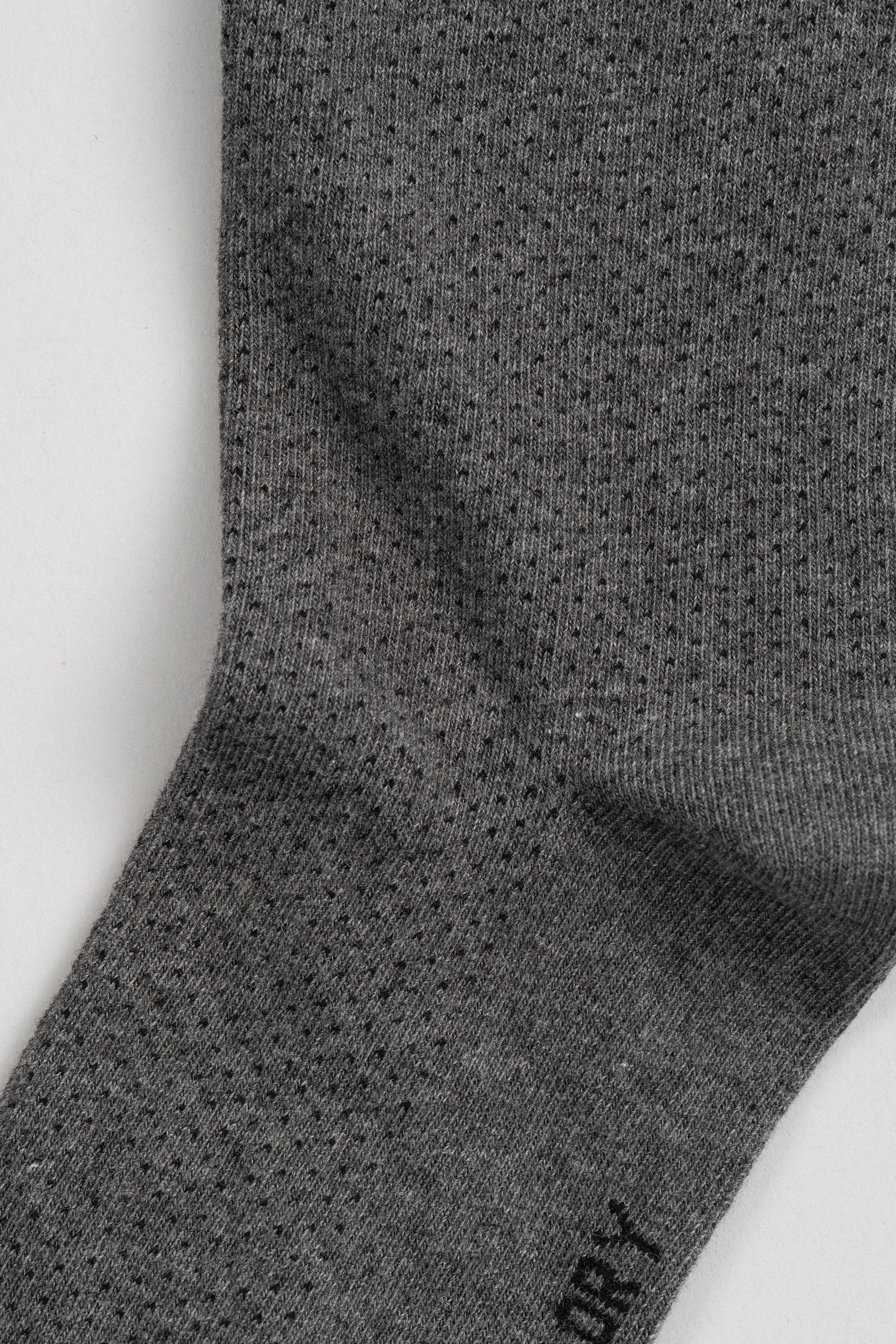 Close-up of Twillory’s Grey Pin Dot sock, featuring a subtle ribbed texture and small dotted pattern. The fine knit fabric and seamless construction make it perfect for updating your sock collection against a plain white background.