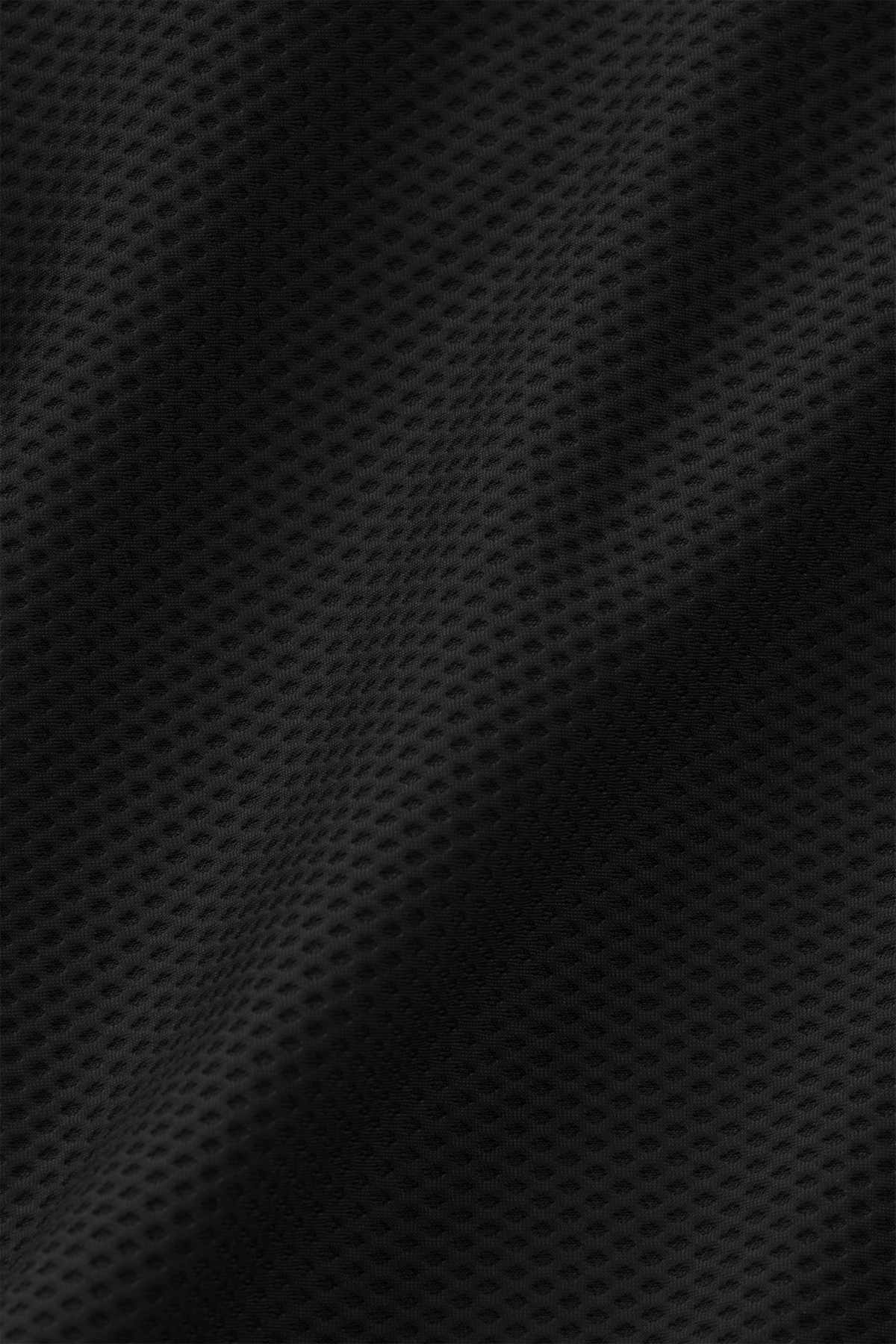 Close-up of black 360° Airflow Fabric with wavy texture on the Twillory AIR Bomber // Heather Charcoal. The grid of small, evenly spaced holes forms a breathable layer and sporty look, highlighted by the lighting along its contours.