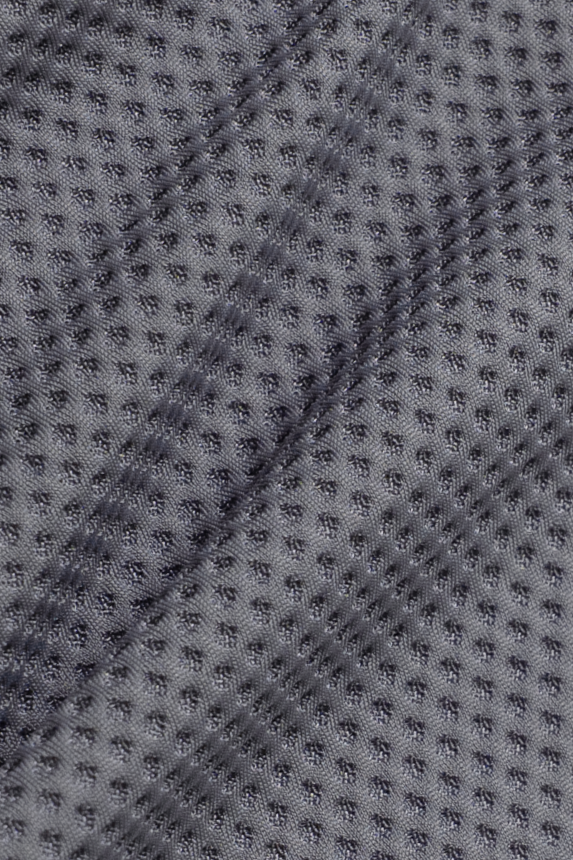 Close-up of the AIR Shorts by Twillory shows grey, sweat-wicking fabric with a grid of small raised dots. The texture and subtle wrinkles catch the light, adding depth to this high-performance design.