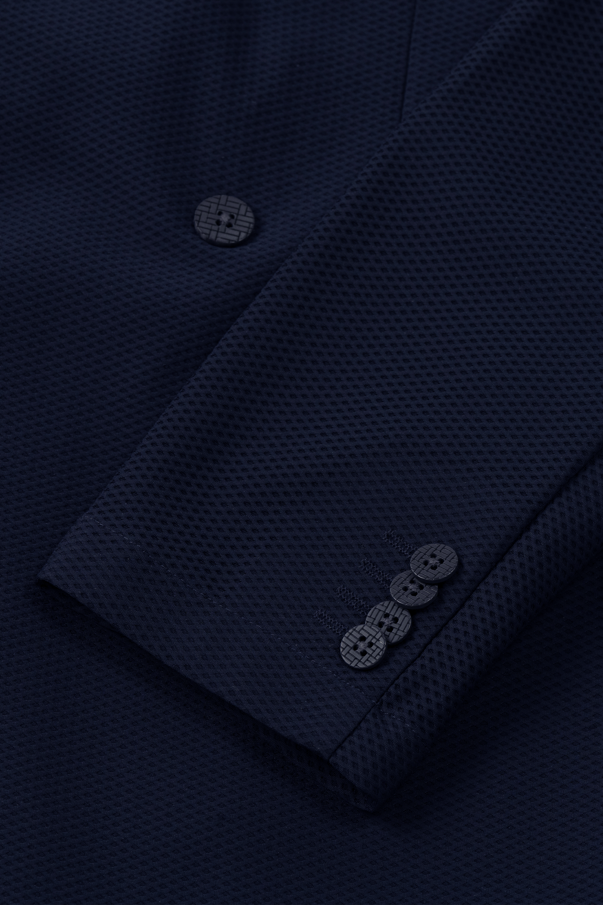 Close-up of the Twillory AIR Double Breasted Blazer // Navy, highlighting its textured 360° Airflow Fabric with a subtle waffle pattern, three matching cuff buttons, and a main front button all in performance fabric.