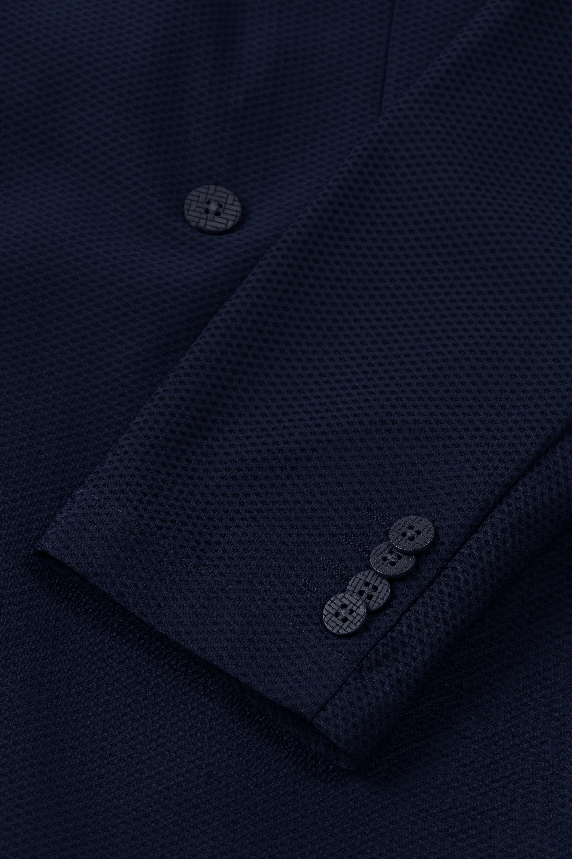 Close-up of the Twillory AIR Double Breasted Blazer // Navy, highlighting its textured 360° Airflow Fabric with a subtle waffle pattern, three matching cuff buttons, and a main front button all in performance fabric.