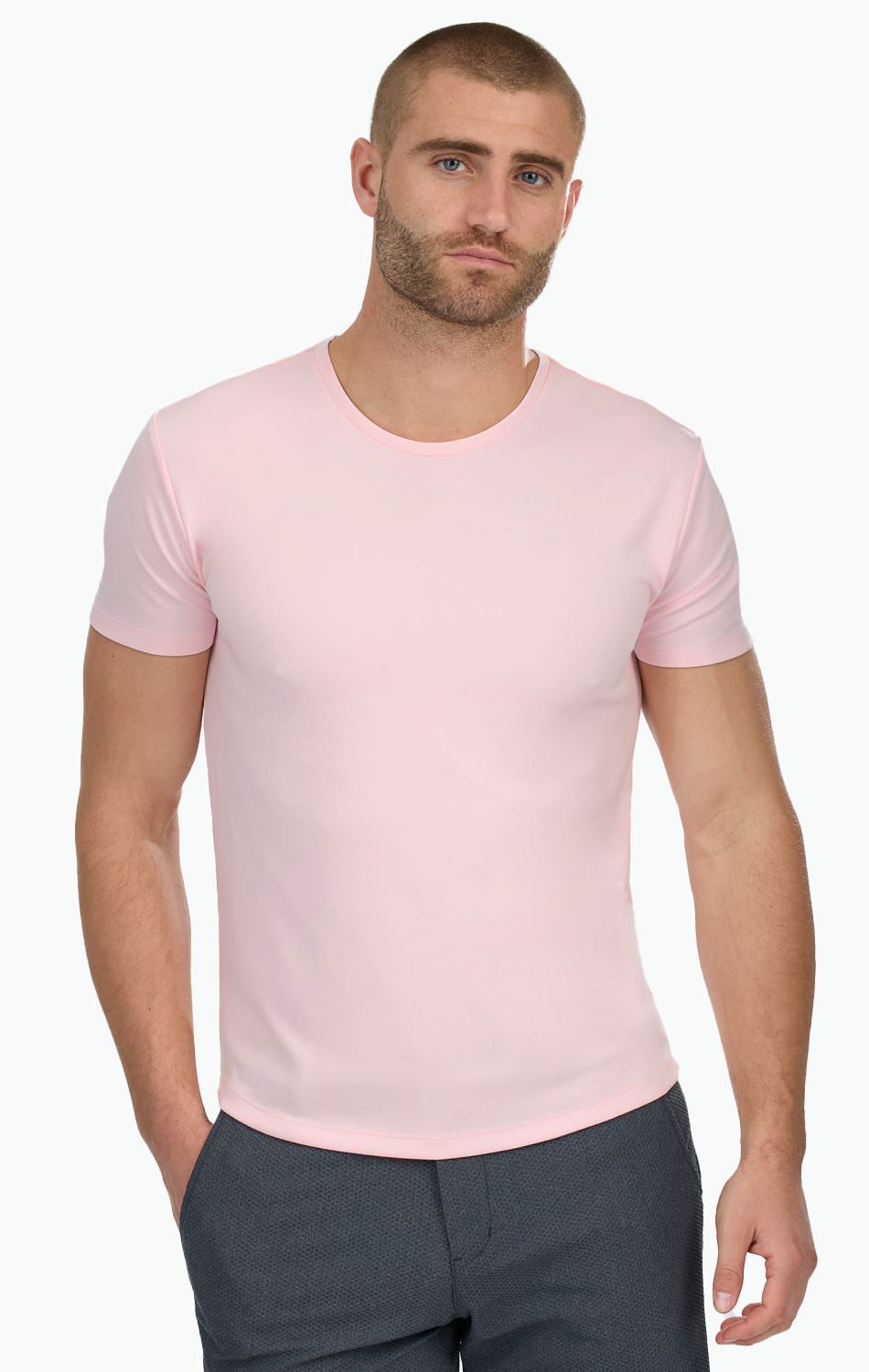 Man wearing a light pink t-shirt and dark gray pants against a white background.