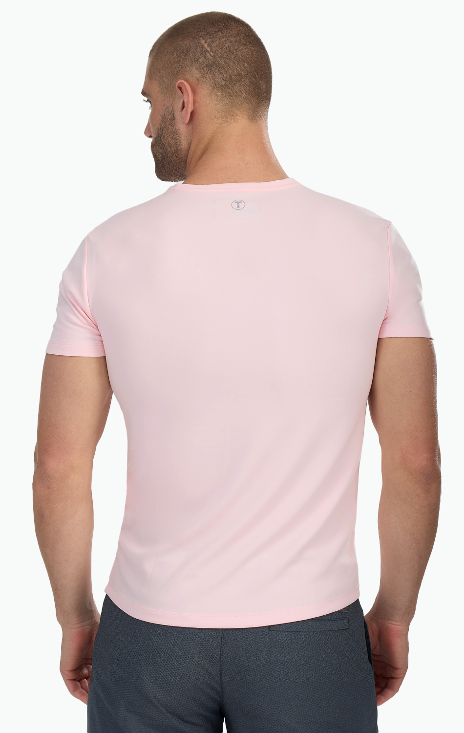 Man wearing a pink fitted t-shirt viewed from the back, showcasing the shirt's slim fit design and color.