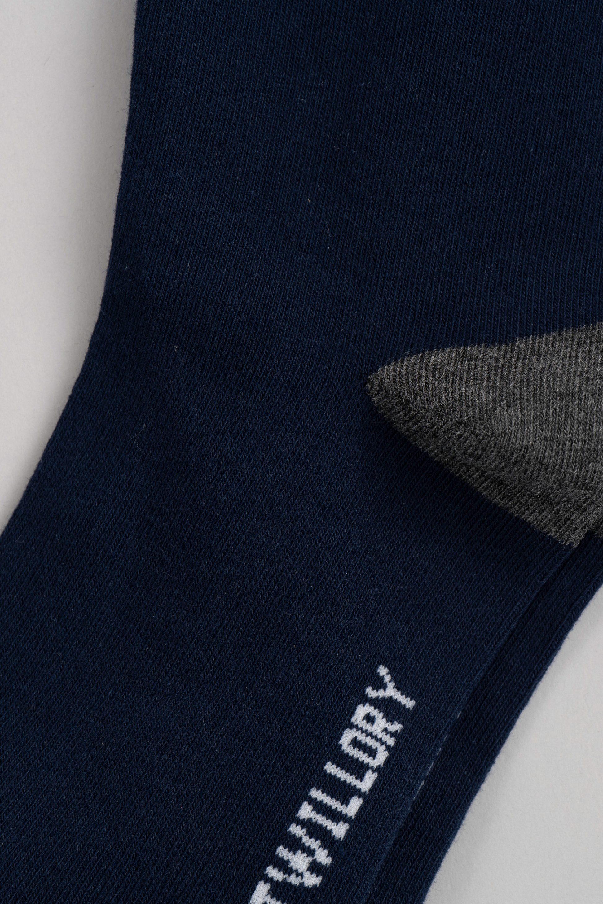 Close-up of the Twillory Navy Solid sock featuring a gray heel and “WILDRY” in white text on the sole, displayed flat on a light gray background—ideal for those seeking their new go-to socks.