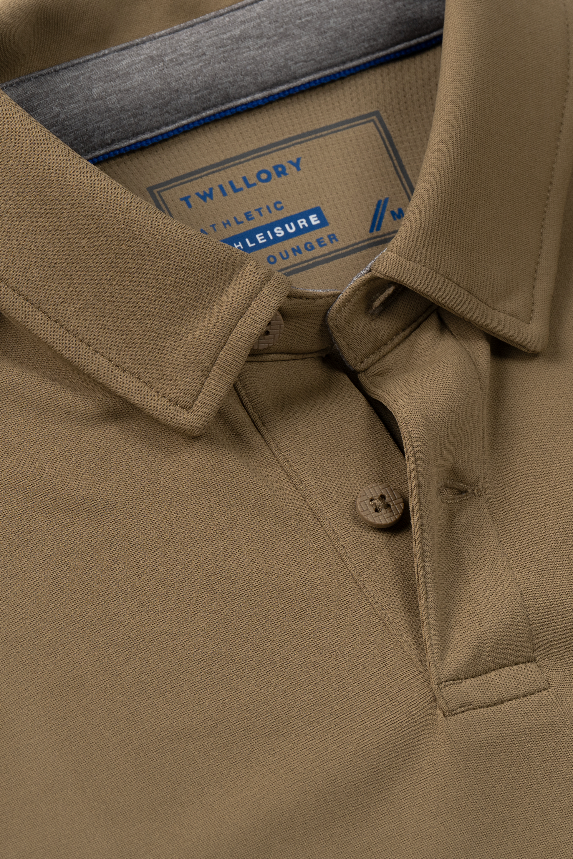 Close-up of the Twillory Short Sleeve Polo Solid in Tobacco, featuring a collar and two buttons. This polo offers a smooth, soft feel with moisture-wicking comfort for all-day wear. The inside label reads “Twillory Athletic Leisure Lounger.”.