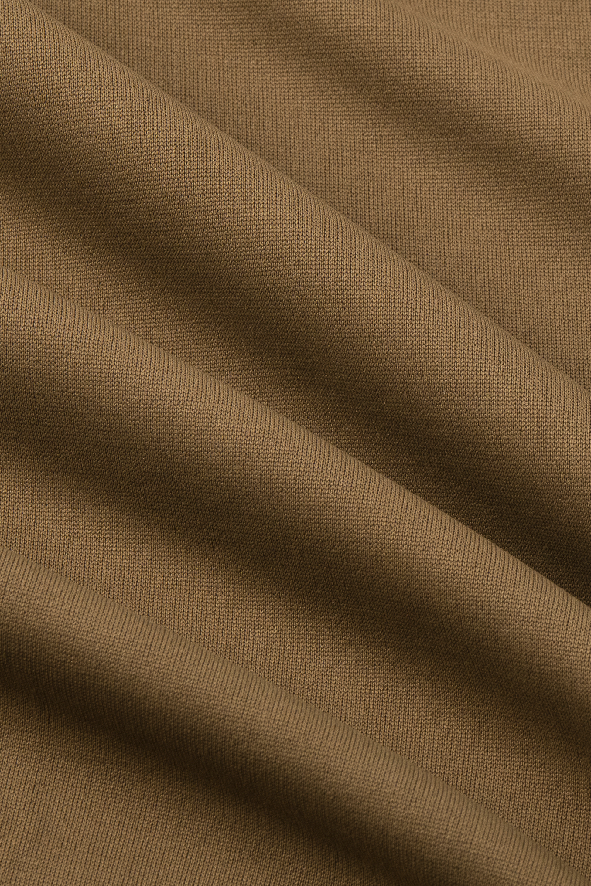 Close-up of the Twillory Short Sleeve Polo Solid in Tobacco. Soft, matte fabric with smooth diagonal folds showcases its comfortable, stretchy knit—perfect for a tailored fit in this performance polo shirt.
