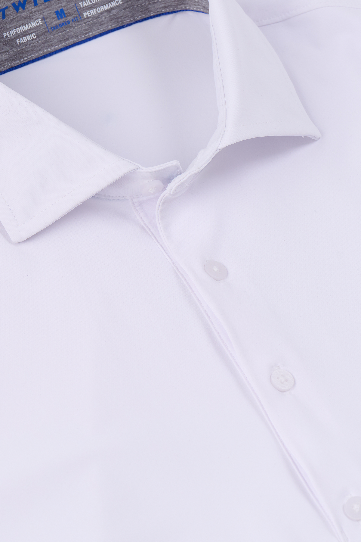 A close-up of Twillory's Event Polo Solid in white, neatly folded to showcase its crisp collar, buttons, and stretchy wrinkle-free fabric. The smooth, clean finish highlights the label text inside the collar.