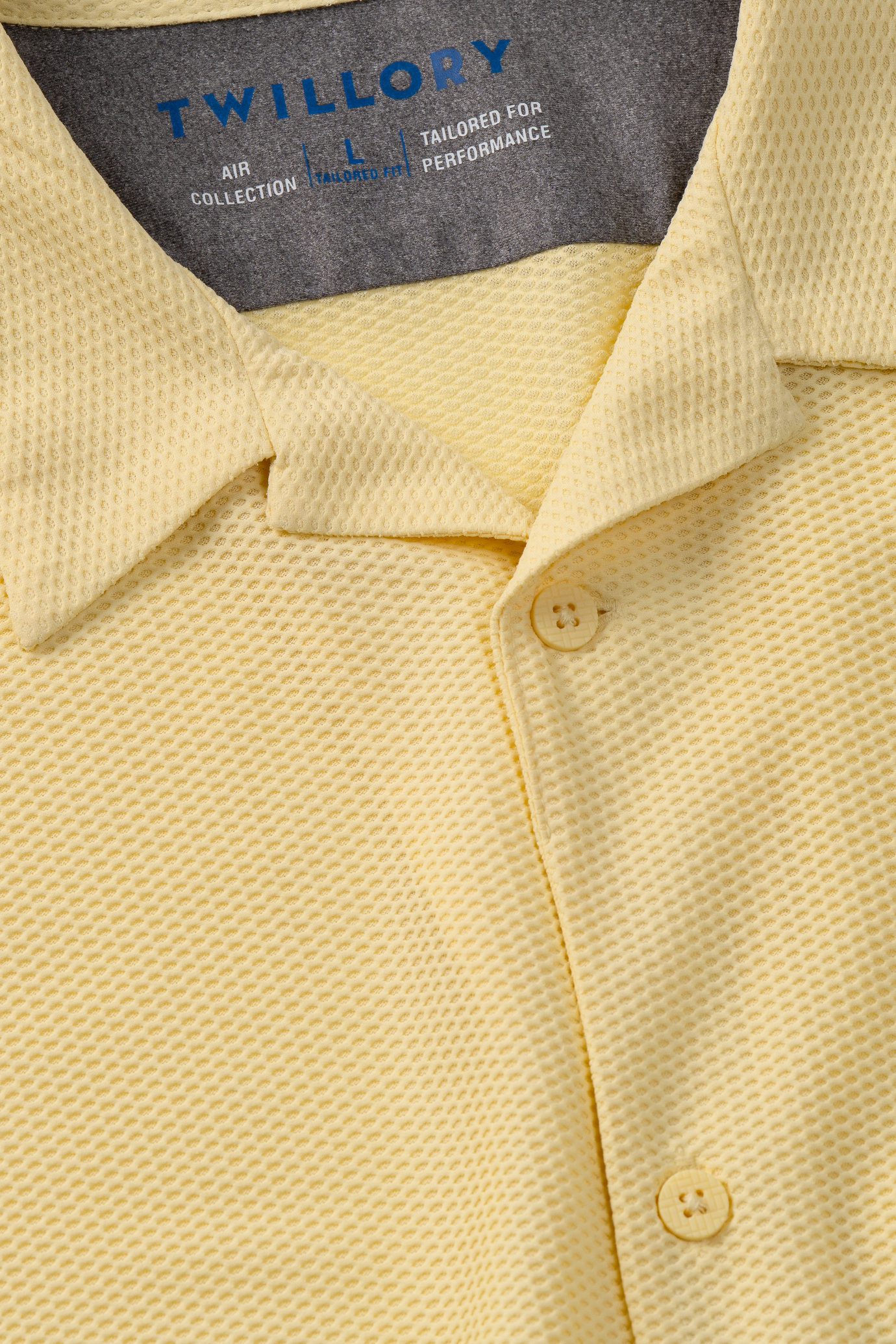 Close-up of Twillory's AIR Resort Shirt Solid in yellow, featuring a textured, waffle-like pattern, short sleeves, collar, and two buttons. Made from cooling AIR fabric for hyper-breathability and tailored performance.