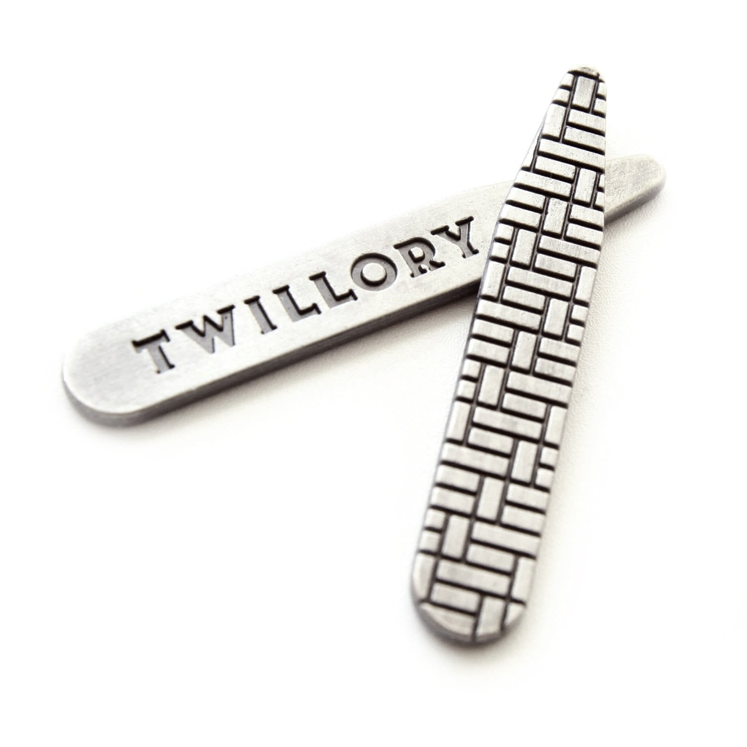 Metal collar stays by Twillory with engraved brand name and a textured pattern on a white background.