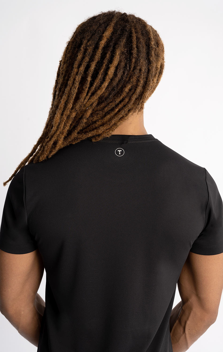Person with long dreadlocks wearing a black t-shirt viewed from the back.
