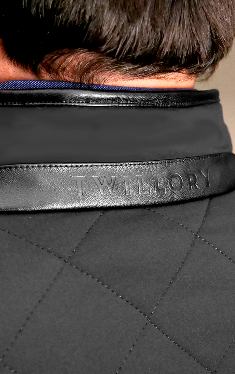 Close-up of a quilted jacket collar with the brand name Twillory embossed on the leather trim.