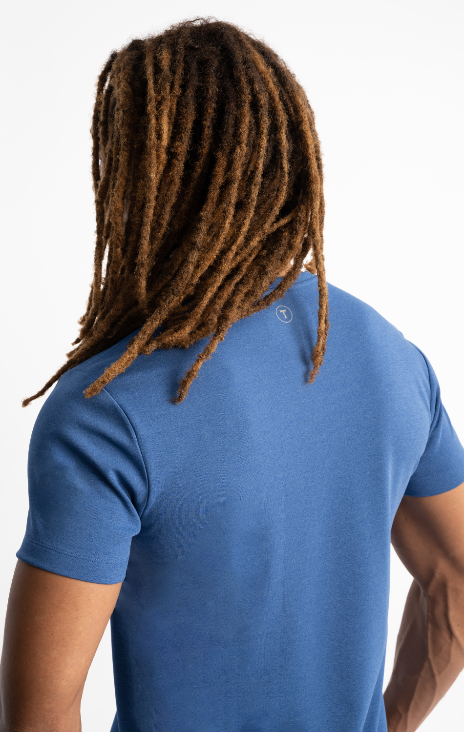 Person with long dreadlocks wearing a blue T-shirt, viewed from behind.