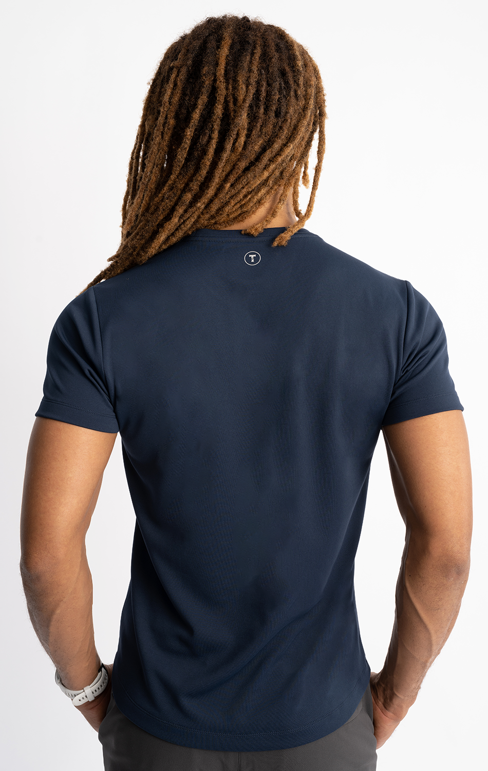 Person with dreadlocks wearing a navy blue t-shirt, viewed from the back, showcasing hair and garment detail.