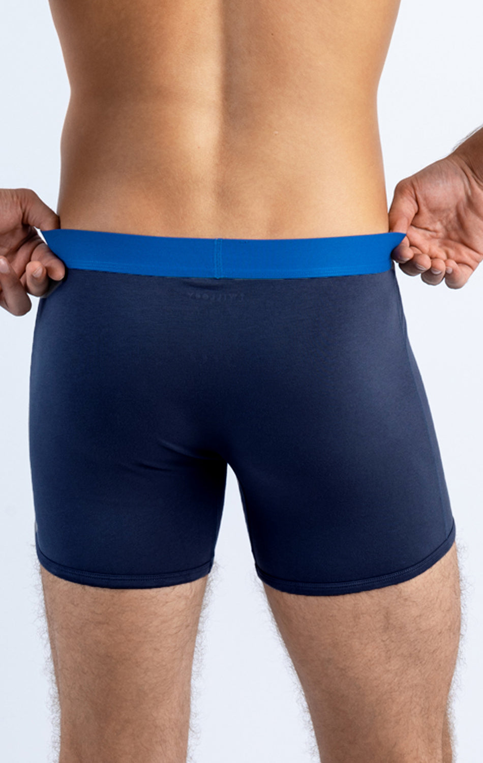 Rear view of a person wearing dark blue boxer briefs with a bright blue waistband.