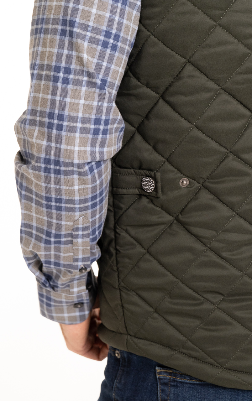 Person wearing a blue plaid shirt and green quilted vest viewed from the side.