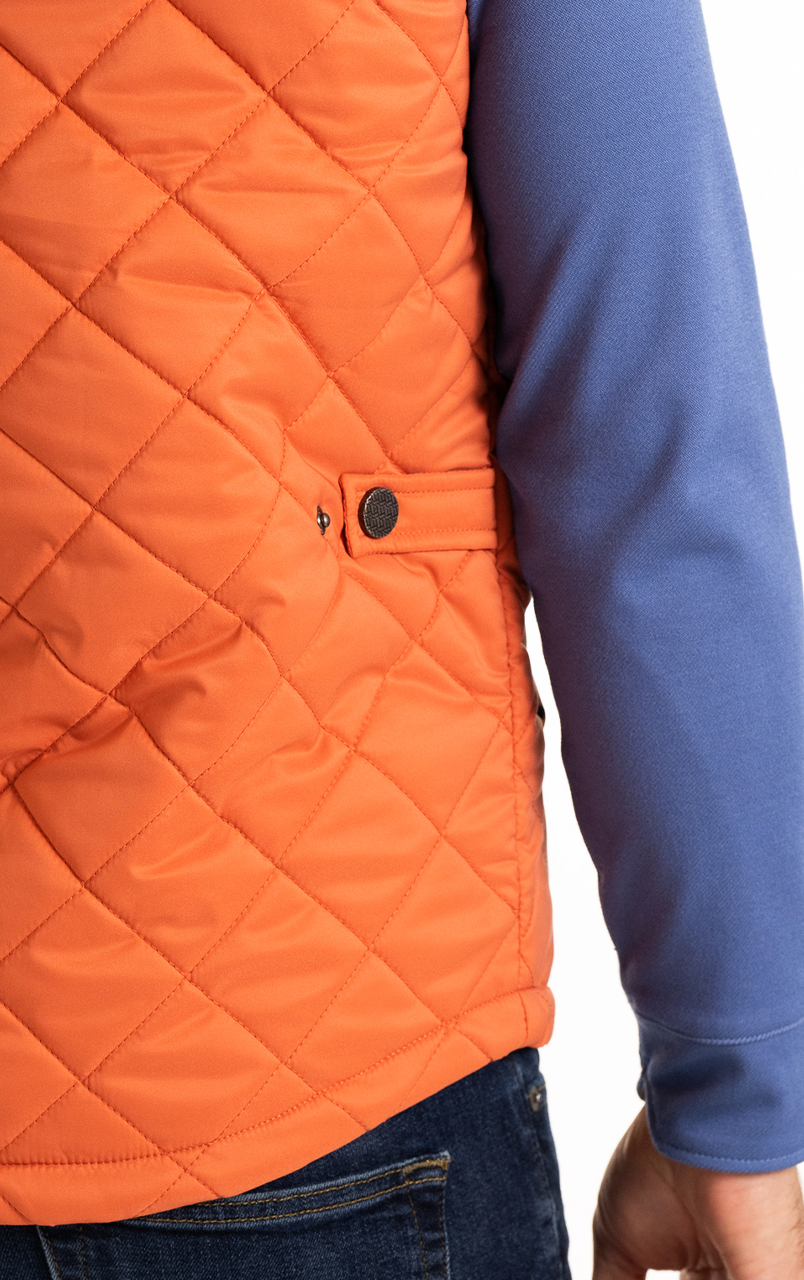 Close-up of a person wearing an orange quilted jacket with a blue sleeve.