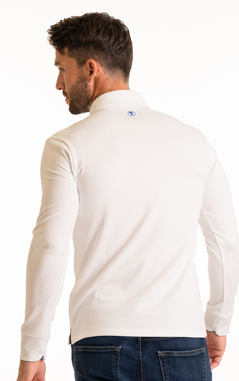 A man with short brown hair and a trimmed beard wears the Twillory Long Sleeve Polo Solid in White, featuring a small blue logo below the neckline. He is shown from the back in blue jeans against a plain white background.