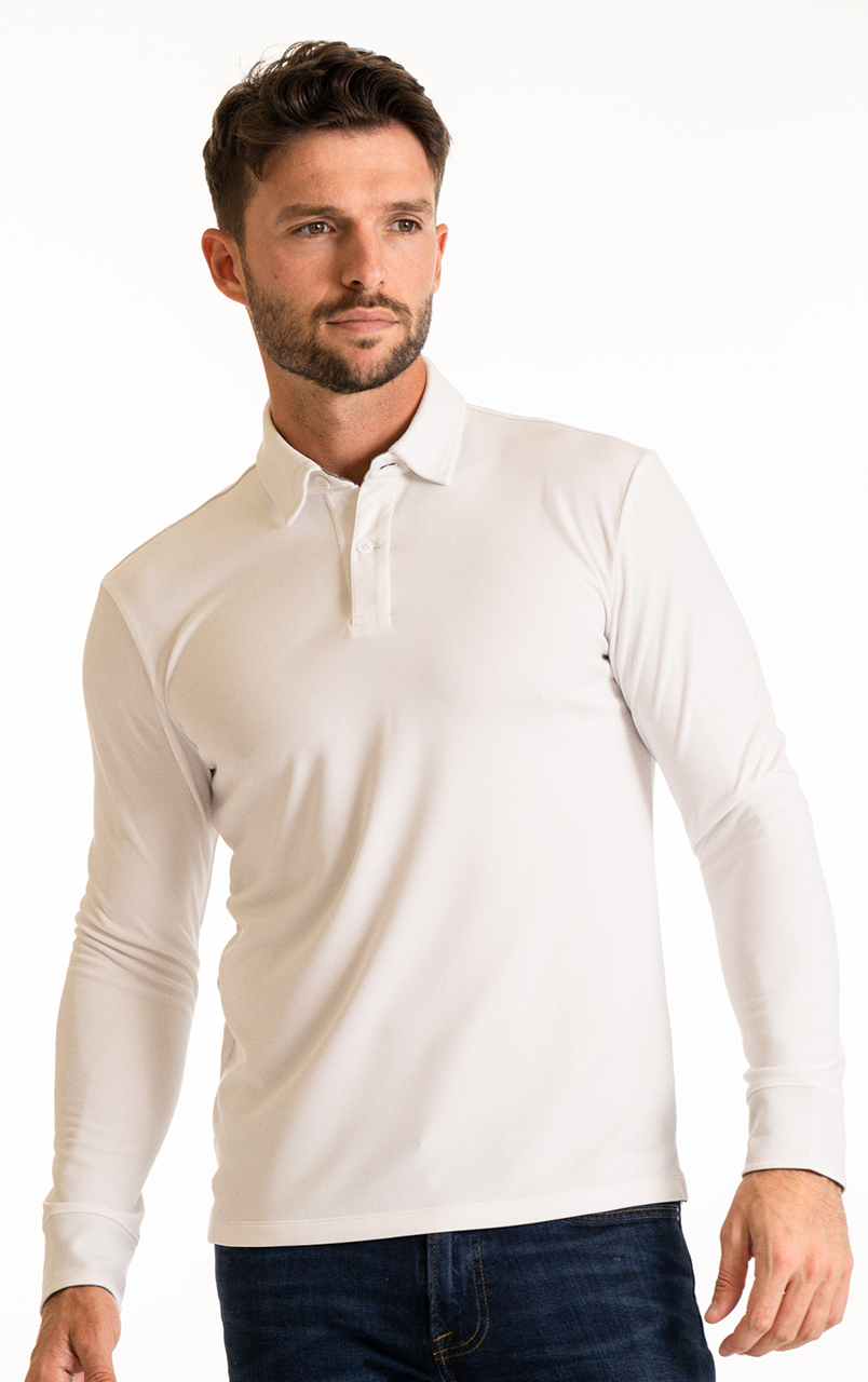 A man with short brown hair and a trimmed beard models the Twillory Long Sleeve Polo Solid in White, paired with dark jeans. He stands against a plain white background, facing slightly to the side with a neutral expression.